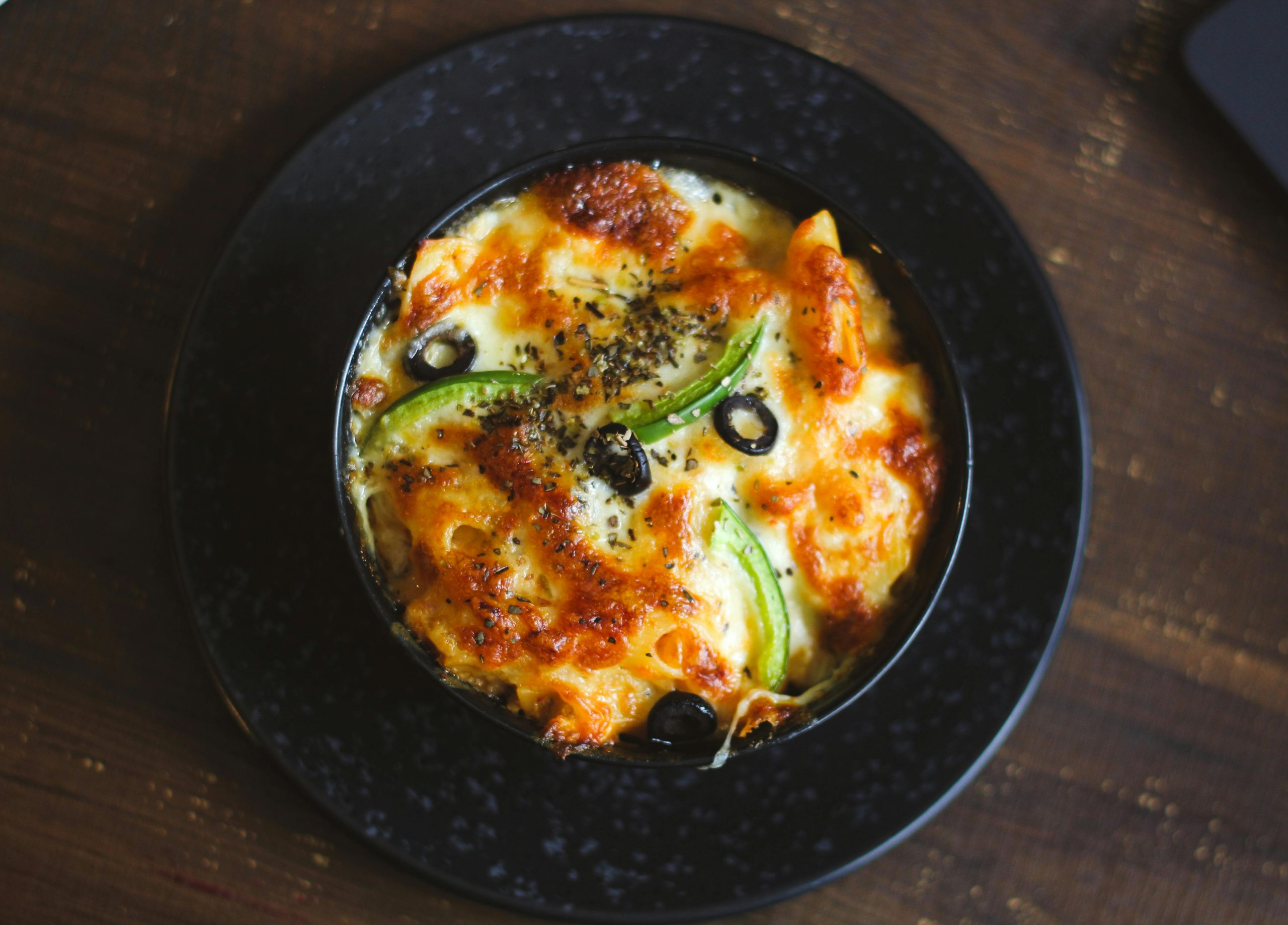 Delicious cheesy baked pasta with black olives and peppers, perfect for a cozy meal.